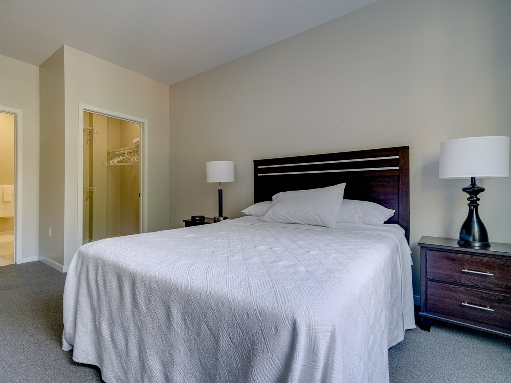 A bedroom with a large bed and two lamps.