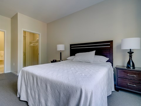A bedroom with a large bed and two lamps.