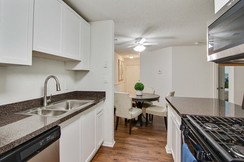 A kitchen with white cabinets and a black dishwasher.