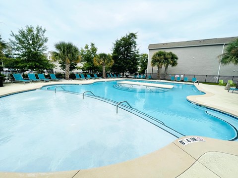 A large outdoor swimming pool with a concrete edge and no people in it.