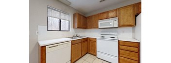 Kitchen with white appliances and wooden cabinets at the Colonial Village Apartments, Lincolnton, North Carolina, 28092. 