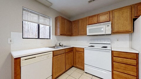 Kitchen with white appliances and wooden cabinets at the Colonial Village Apartments, Lincolnton, North Carolina, 28092. 