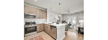 A modern kitchen with wooden cabinets and stainless steel appliances.at The Ashton at East Park Apartments, Kennesaw, 30144