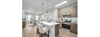 A modern kitchen with a white island and wooden cabinets.at The Ashton at East Park Apartments, Kennesaw, Georgia