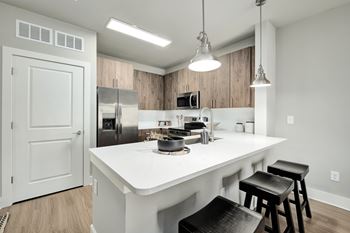 A kitchen with a white countertop and black stools at The Ashton at East Park Apartments, Kennesaw