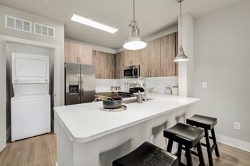 A modern kitchen with a white countertop and black bar stools at The Ashton at East Park Apartments, Georgia