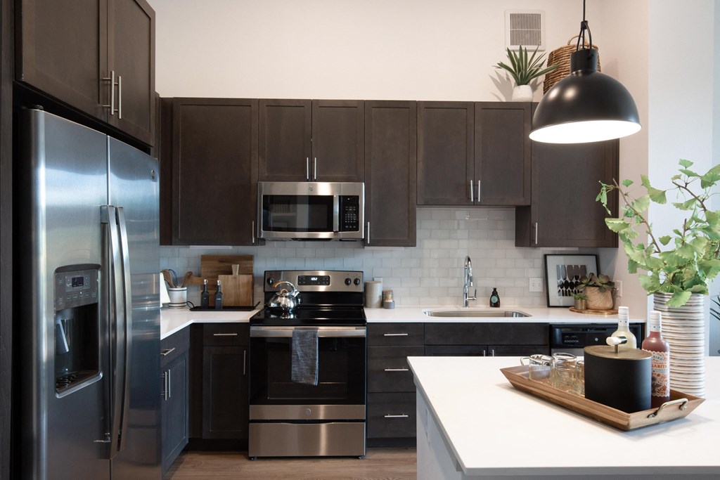 a modern kitchen with stainless steel appliances and dark cabinets at The Monroe Apartments, Austin, Texas