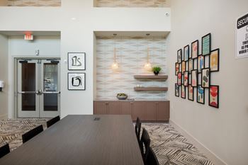 a conference room with a wooden table and chairs and a wall filled with framed art at The Monroe Apartments, Texas, 78741