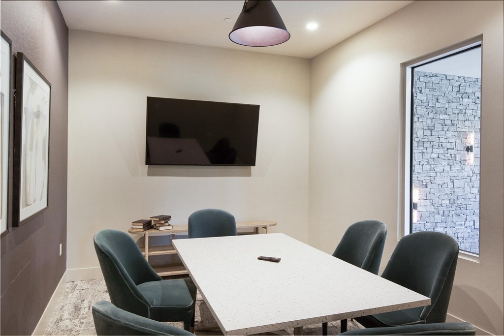 a conference room with a table and chairs and a tv on the wall at The Monroe Apartments, Austin, 78741