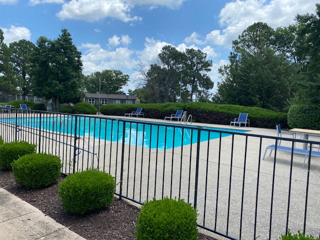 a pool with a fence and chairs around it
