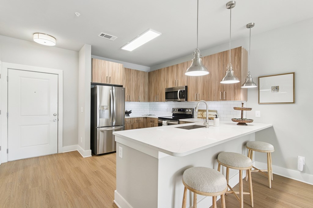 A kitchen with a white countertop and wooden cabinets.at The Delaney at East Park Apartments, Kennesaw