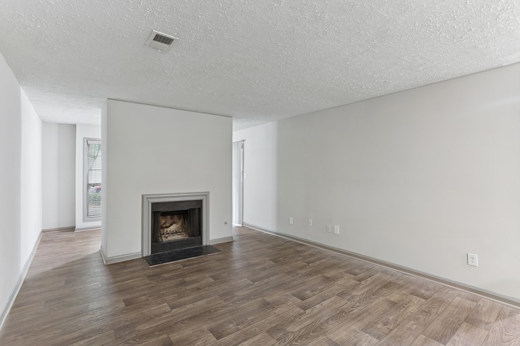 A living room with a fireplace and wood flooring.