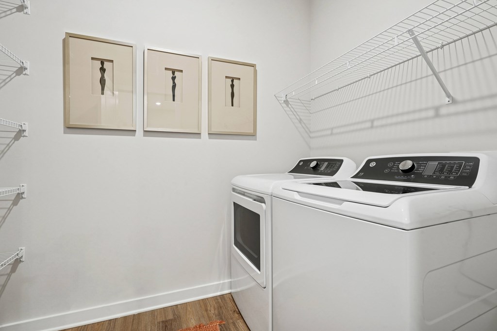 A white wall with three paintings and a white dryer.