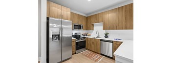 A kitchen with wooden cabinets and a stainless steel refrigerator.