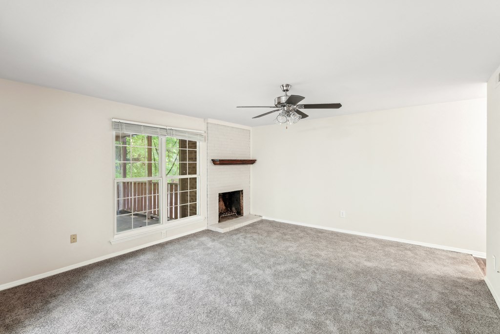 an empty living room with a fireplace and a ceiling fan