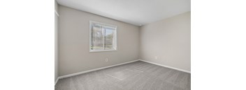 A room with a carpeted floor and a window with blinds.
