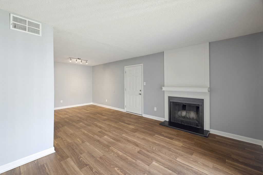 an empty living room with a fireplace and wooden floors  at Governors House, Alabama