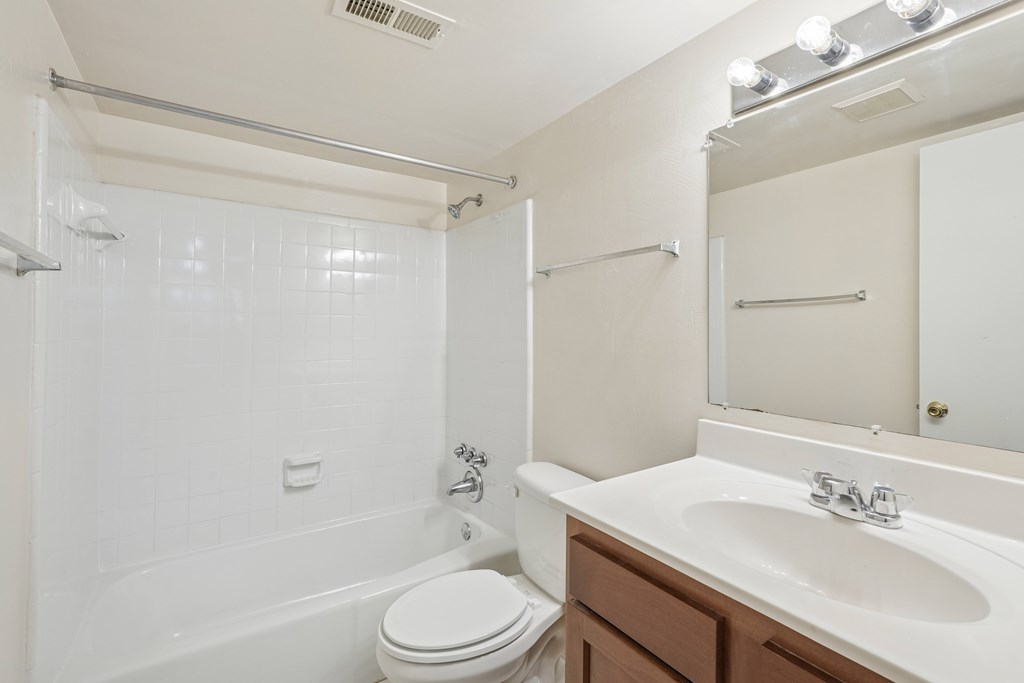A white bathroom with a toilet, sink, and shower.