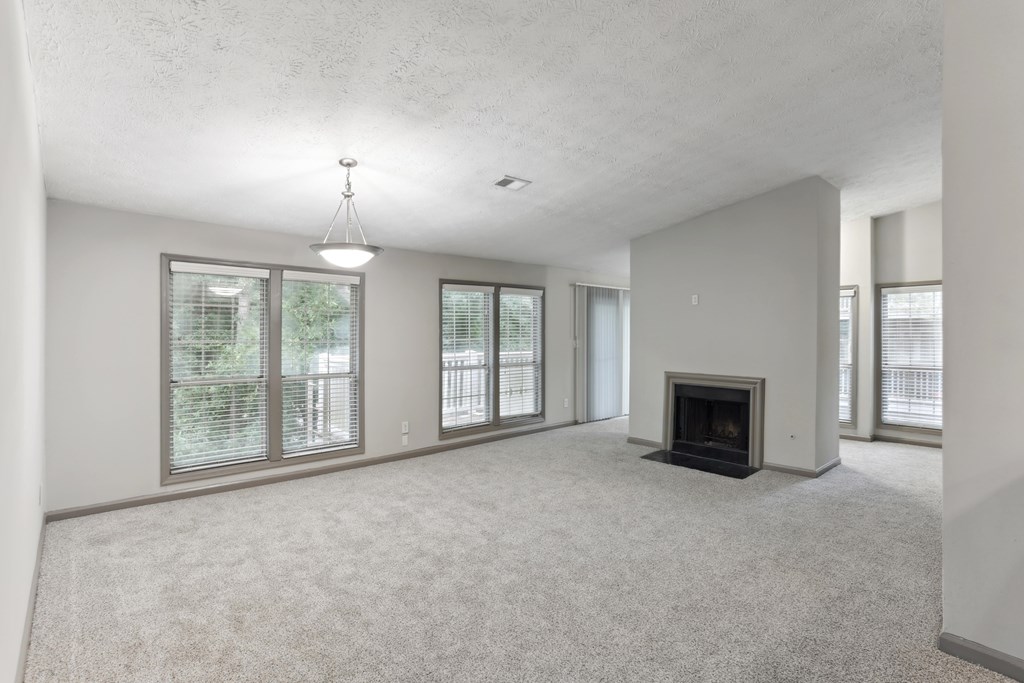 A spacious living room with a fireplace and large windows.