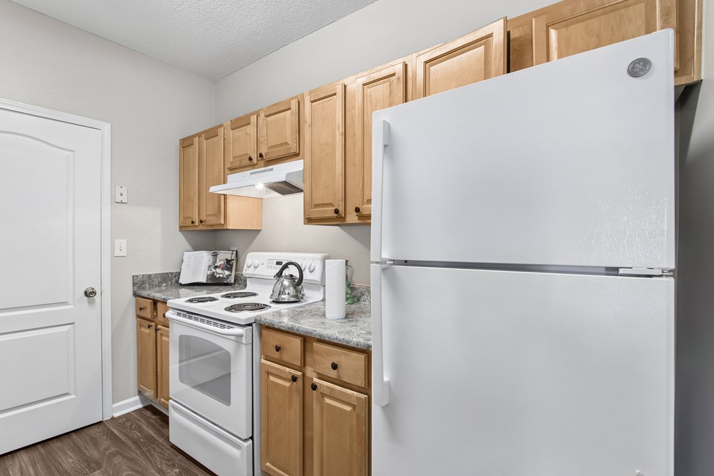 A white refrigerator stands in a kitchen with wooden cabinets.