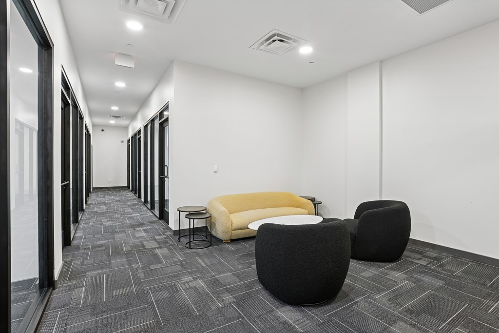 A hallway with a yellow sofa and black chairs.