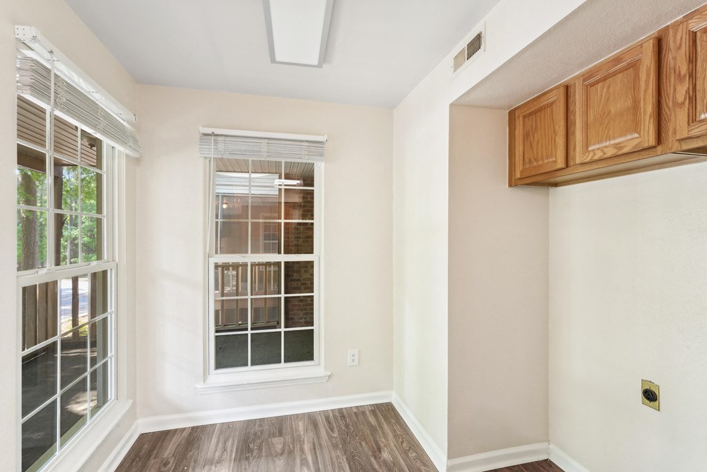 an empty room with a window and wooden floors and cabinets