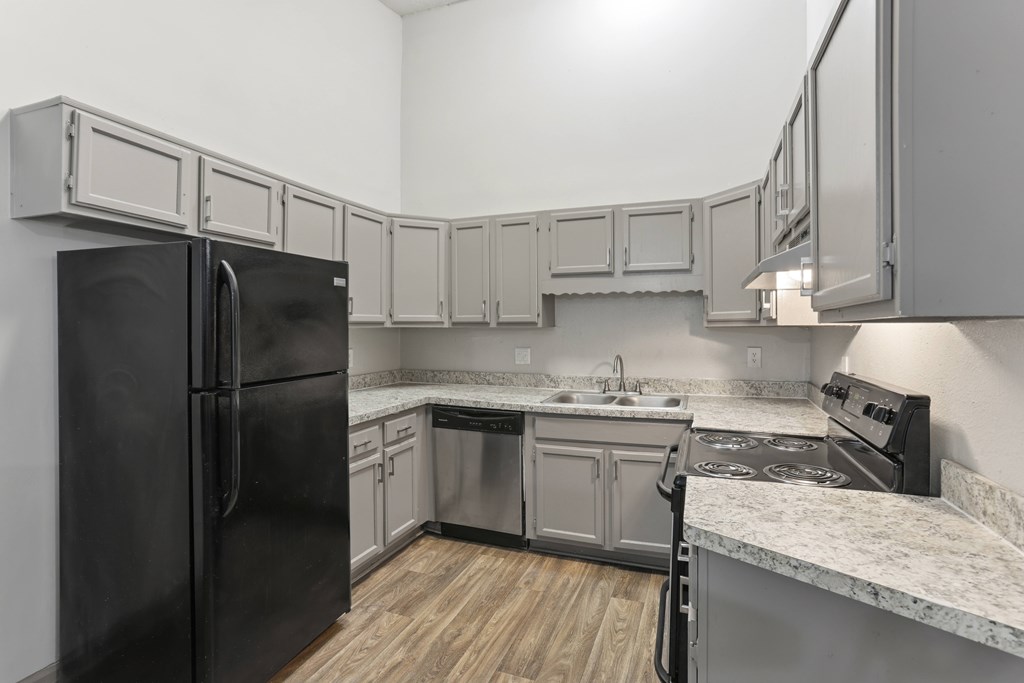 A kitchen with a black refrigerator and a black stove top oven.