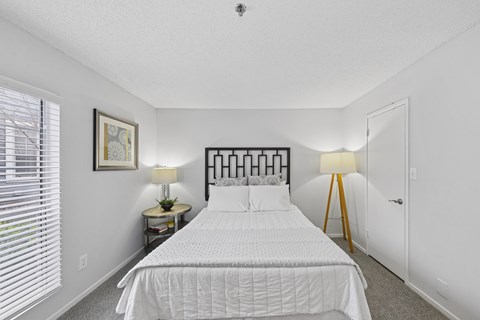 A bedroom with a large bed and two lamps.