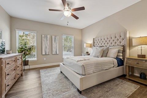 A bedroom with a large bed, a dresser, and a ceiling fan.