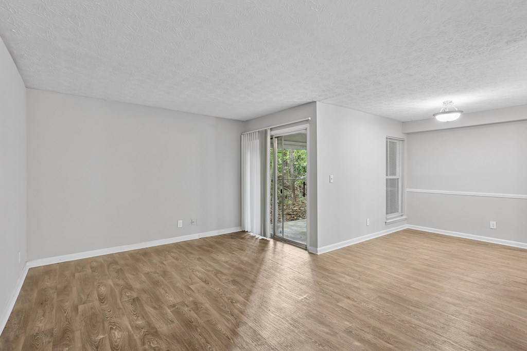 A room with wooden flooring and a sliding glass door leading to a garden.
