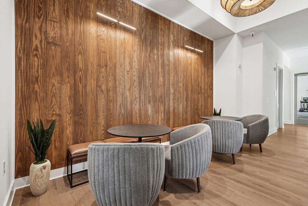 A room with a wooden wall and grey chairs.