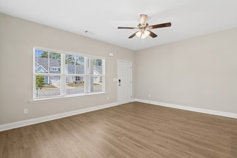 A room with a ceiling fan and a window with blinds.