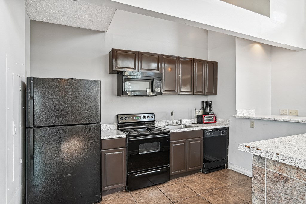 Kitchen with black appliances and brown cabinets  at Wellington Farms, Charlotte