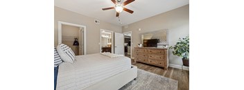 A bedroom with a large bed, a dresser, and a ceiling fan.