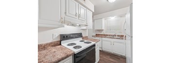 A kitchen with a stove top oven and white cabinets.
