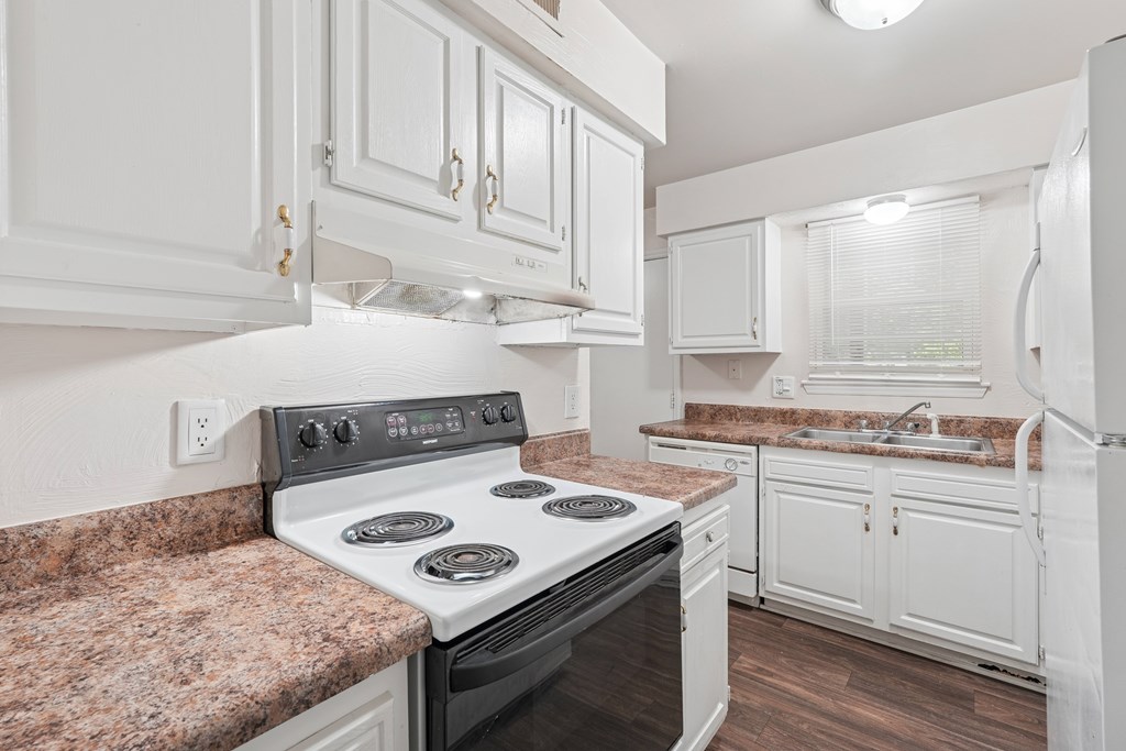 A kitchen with a stove top oven and white cabinets.