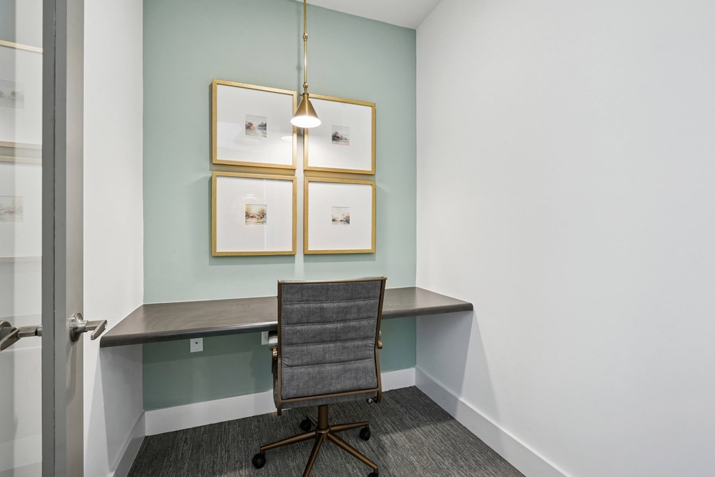 A room with a chair and a table with pictures on the wall.