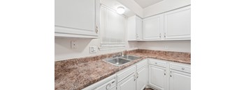 A kitchen with white cabinets and a granite countertop.