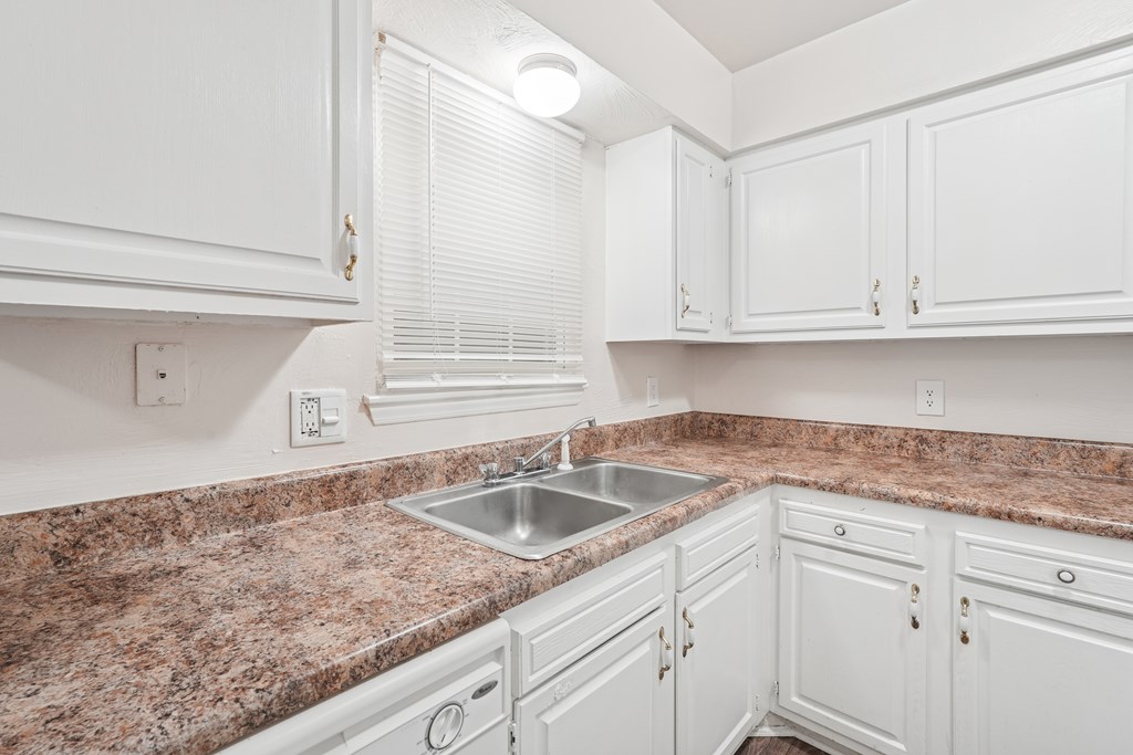 A kitchen with white cabinets and a granite countertop.