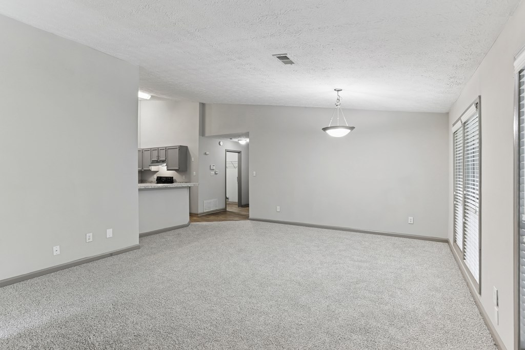 A spacious room with a carpeted floor and a ceiling fan.