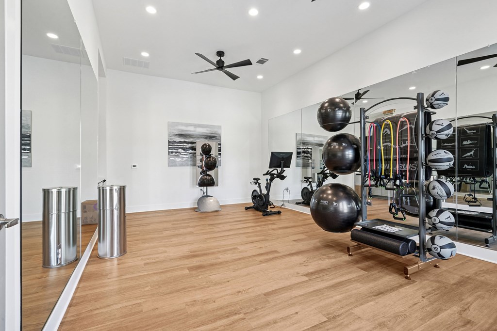 A gym with a variety of equipment including a treadmill, weights, and a fan.
