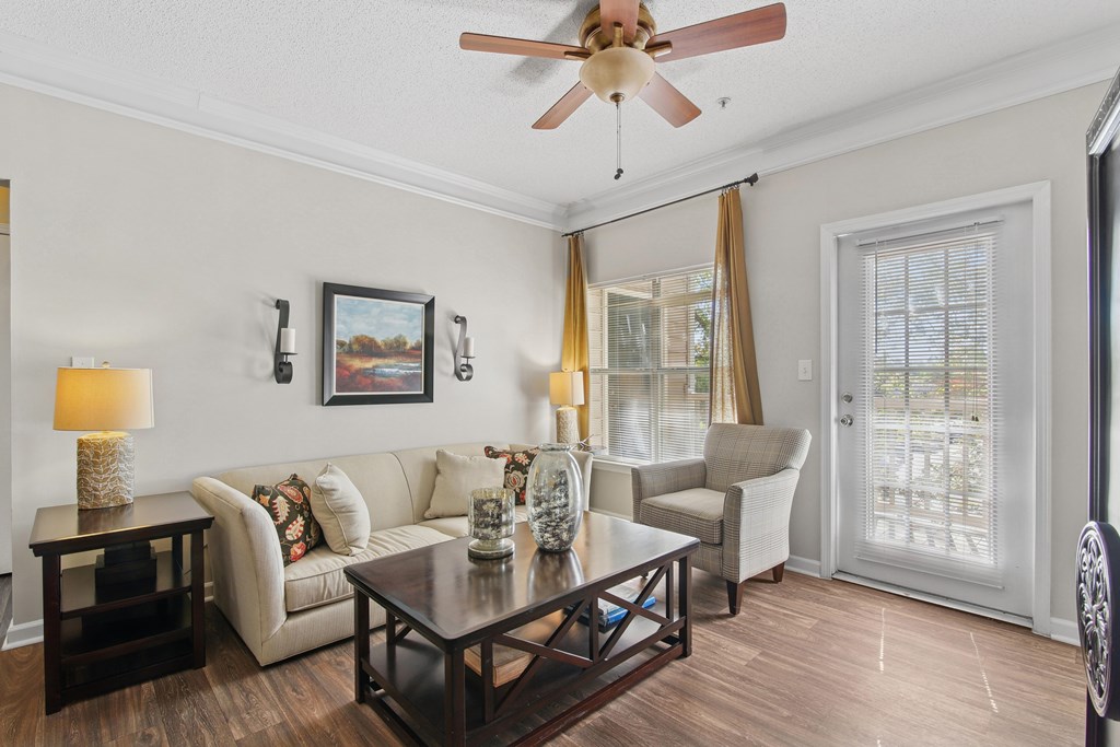 A living room with a white couch, a coffee table, and a ceiling fan.