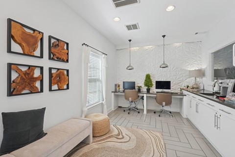 A modern living room with a couch, a desk with a computer, and three abstract paintings on the wall.