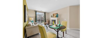 A living room with a yellow chair and a fireplace.