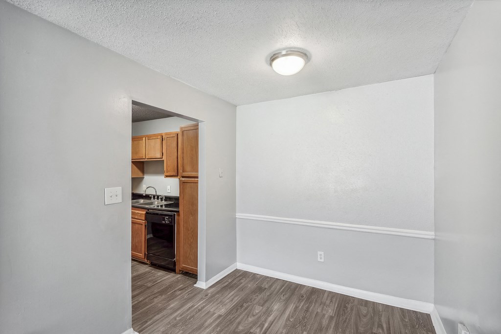 an empty living room and kitchen with wood flooring and white walls