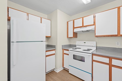A white refrigerator is in a kitchen with wooden cabinets.