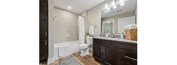 A white toilet sits in a bathroom with a white tub and a white shower curtain.