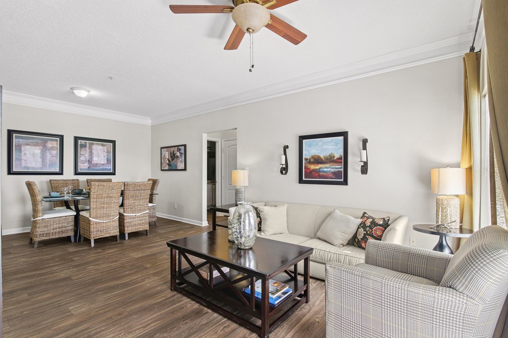 A living room with a couch, chairs, and pictures on the wall.