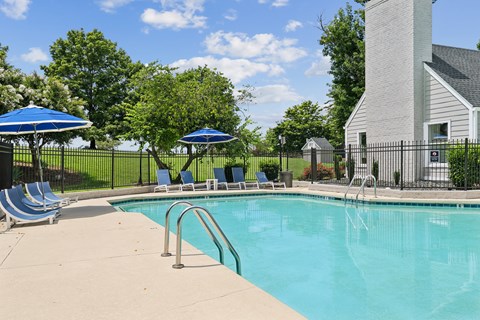 A pool with a fence and a building in the background.