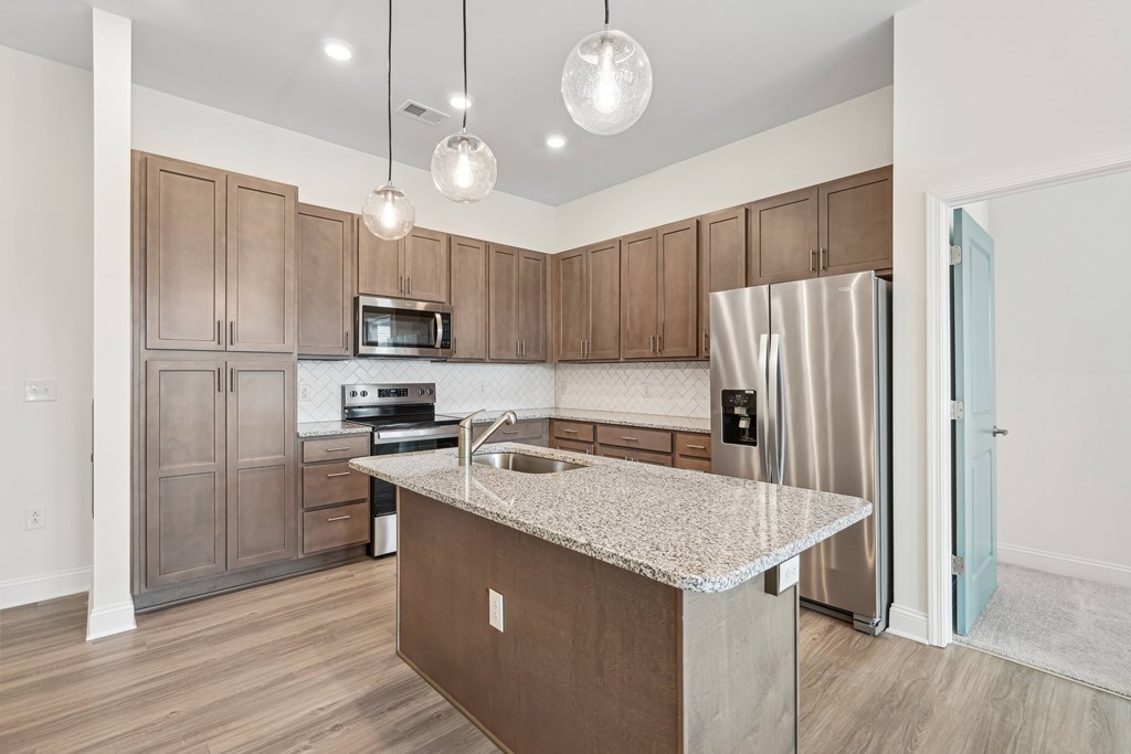 A kitchen with brown cabinets and a granite countertop.at The Parker Leland, Leland, 28451  